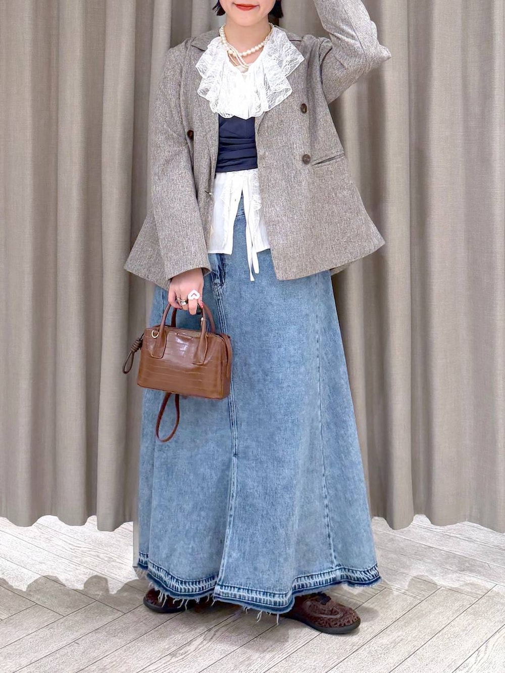 ベージュ系のテーラードジャケット、ブルー系のデニムスカート、ブラウン系のトートバッグを着用したレディースの冬コーディネートの8枚目の写真