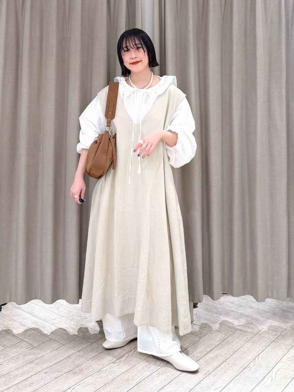 ベージュ系のジャンパースカート、ベージュ系のパンプス、ベージュ系のトートバッグを着用したレディースの冬コーディネートの9枚目の写真