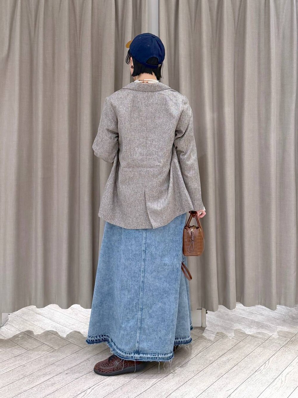 ベージュ系のテーラードジャケット、ブルー系のデニムスカート、ブラウン系のトートバッグを着用したレディースの冬コーディネートの4枚目の写真