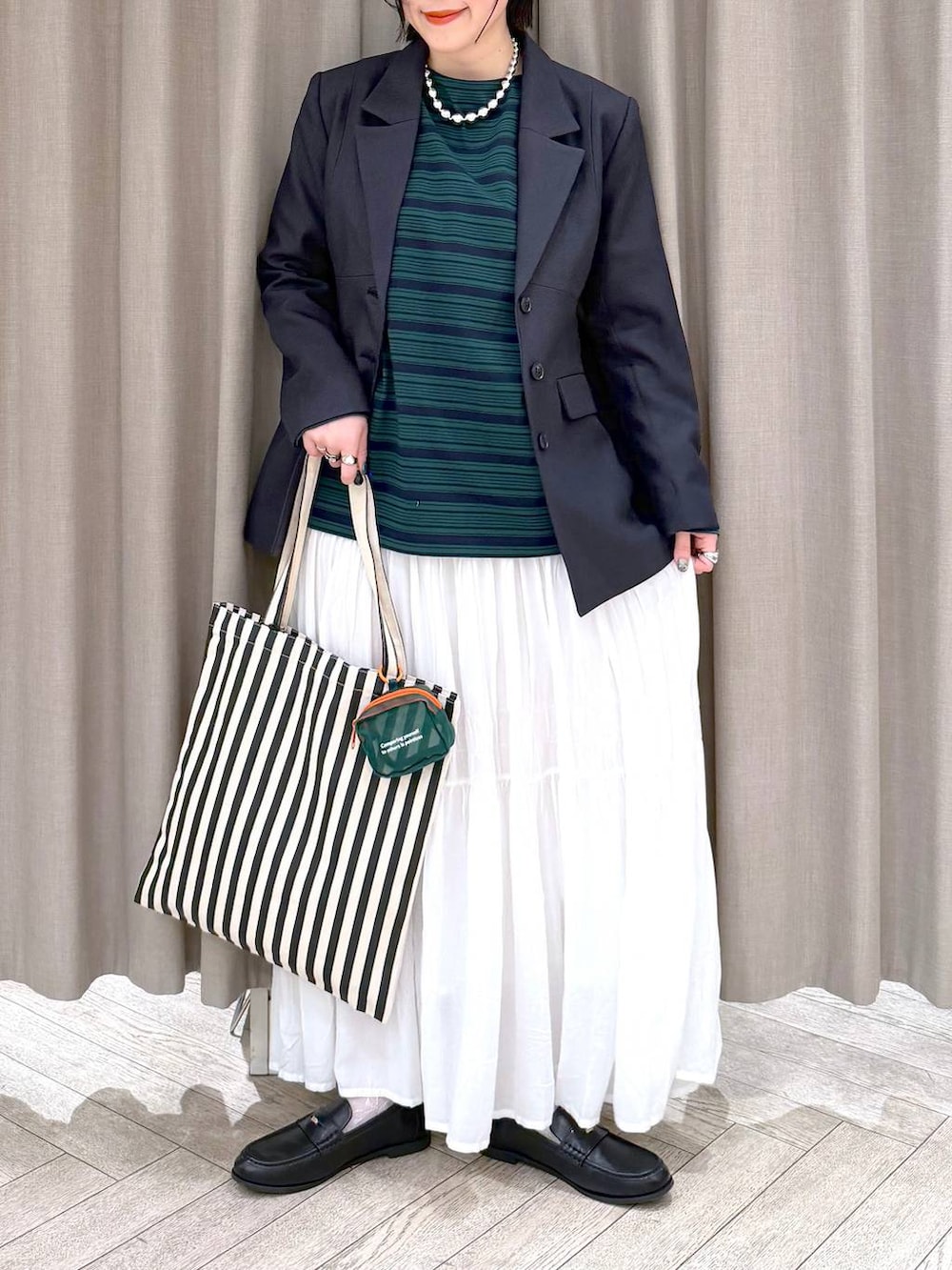 ホワイト系のスカート、ブラック系のローファー、ベージュ系のトートバッグを着用したレディースの冬コーディネートの7枚目の写真