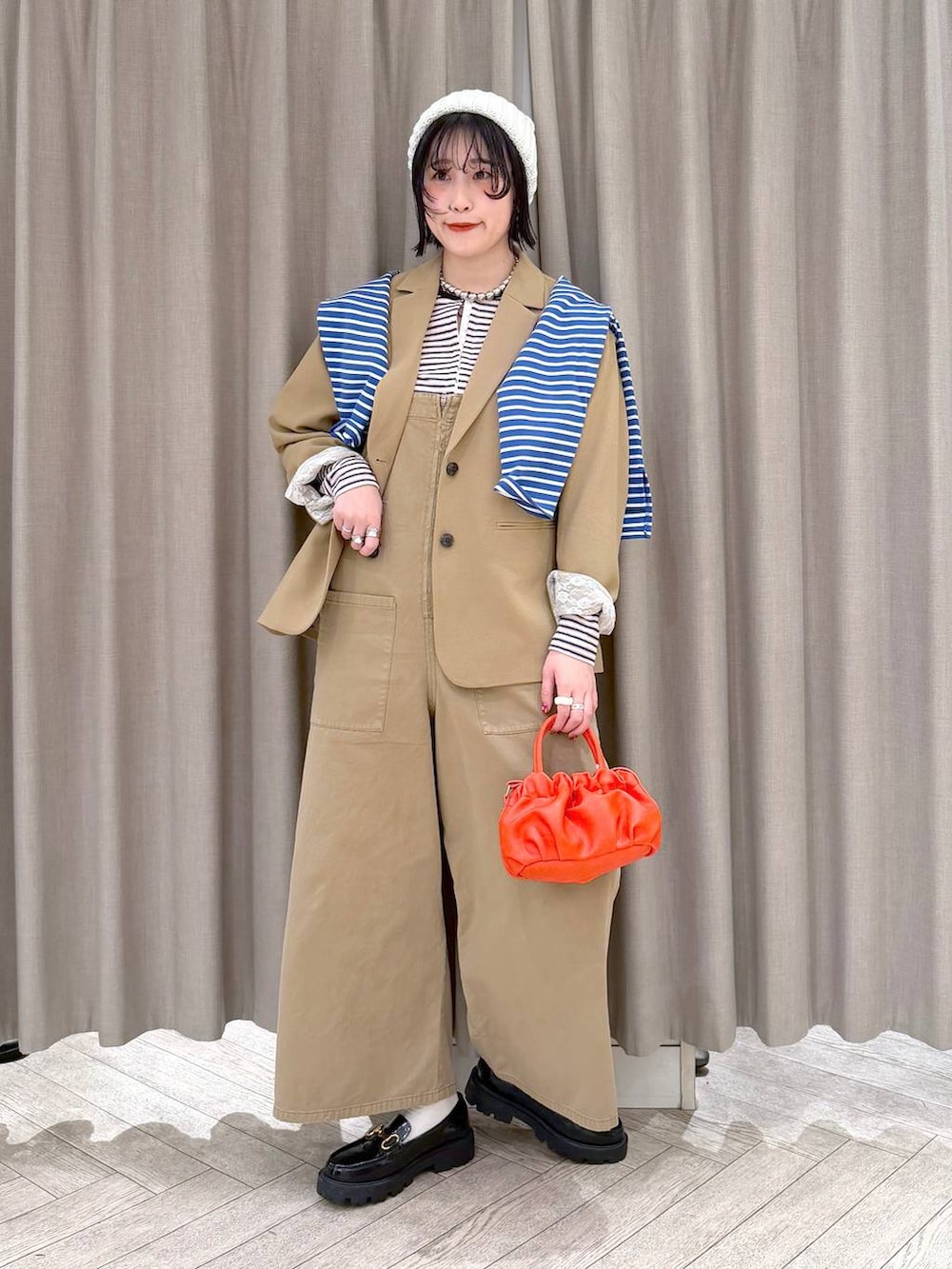 ブラック系のローファー、ベージュ系のサロペット/オーバーオール、オレンジ系のショルダーバッグを着用したレディースの冬コーディネートの2枚目の写真