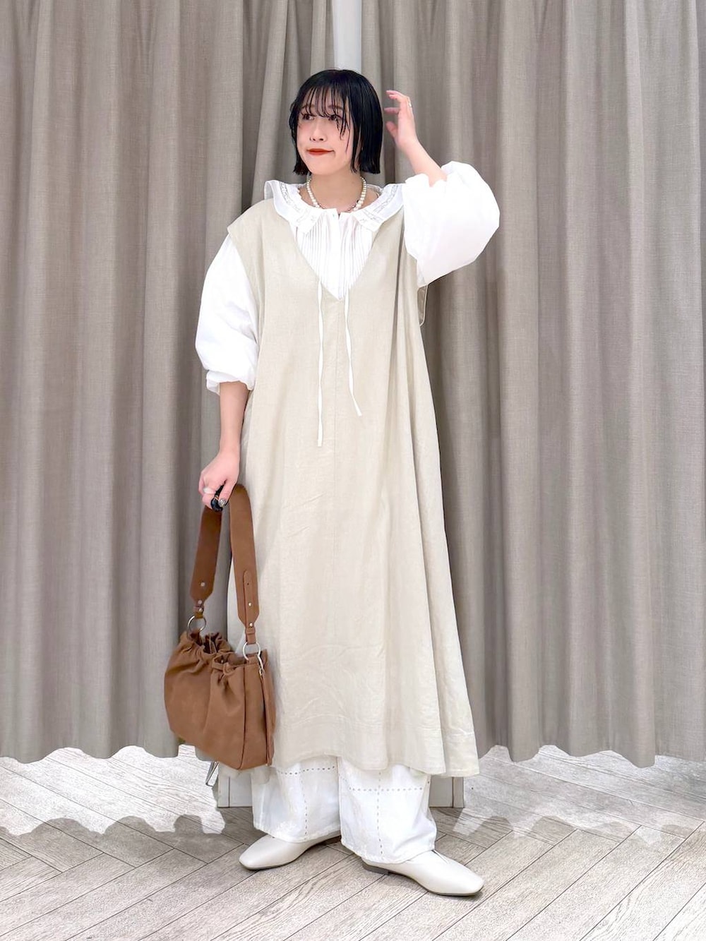 ベージュ系のジャンパースカート、ベージュ系のパンプス、ベージュ系のトートバッグを着用したレディースの冬コーディネートの3枚目の写真