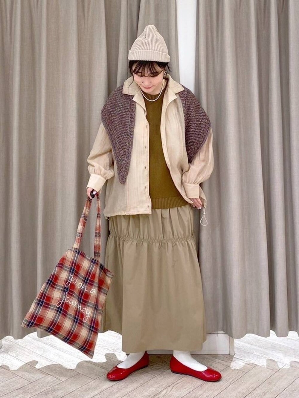 レッド系のパンプス、ベージュ系のナイロンジャケット、ベージュ系のワンピースを着用したレディースの秋コーディネートの9枚目の写真