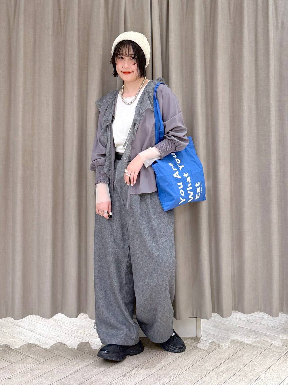 ホワイト系のTシャツ/カットソー、グレー系のスラックス、ブルー系のトートバッグを着用したレディースの冬コーディネートの2枚目の写真