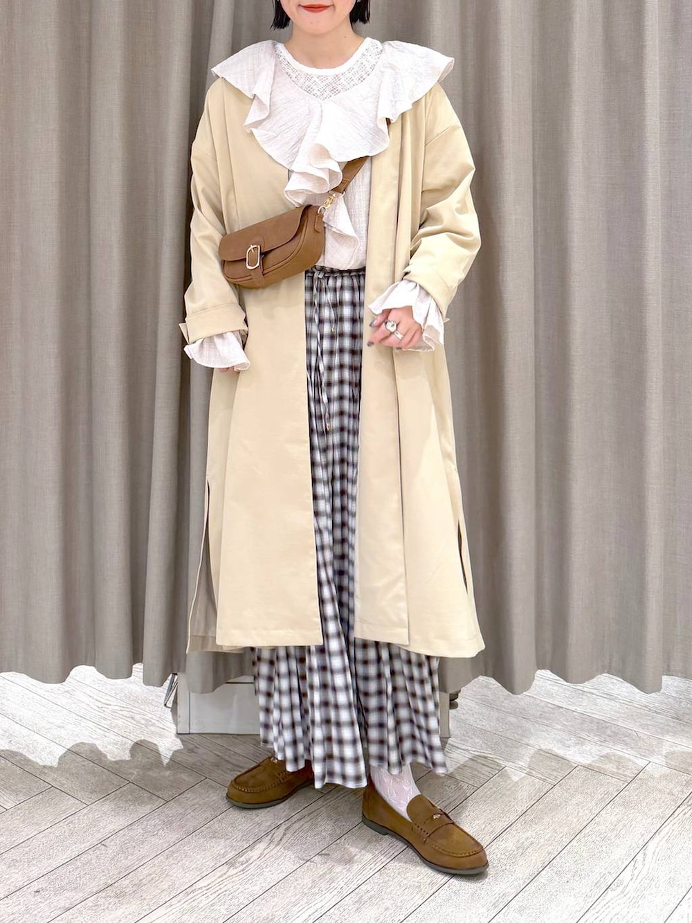 イエロー系のショルダーバッグ、ベージュ系のチェスターコート、イエロー系のローファーを着用したレディースの冬コーディネートの7枚目の写真