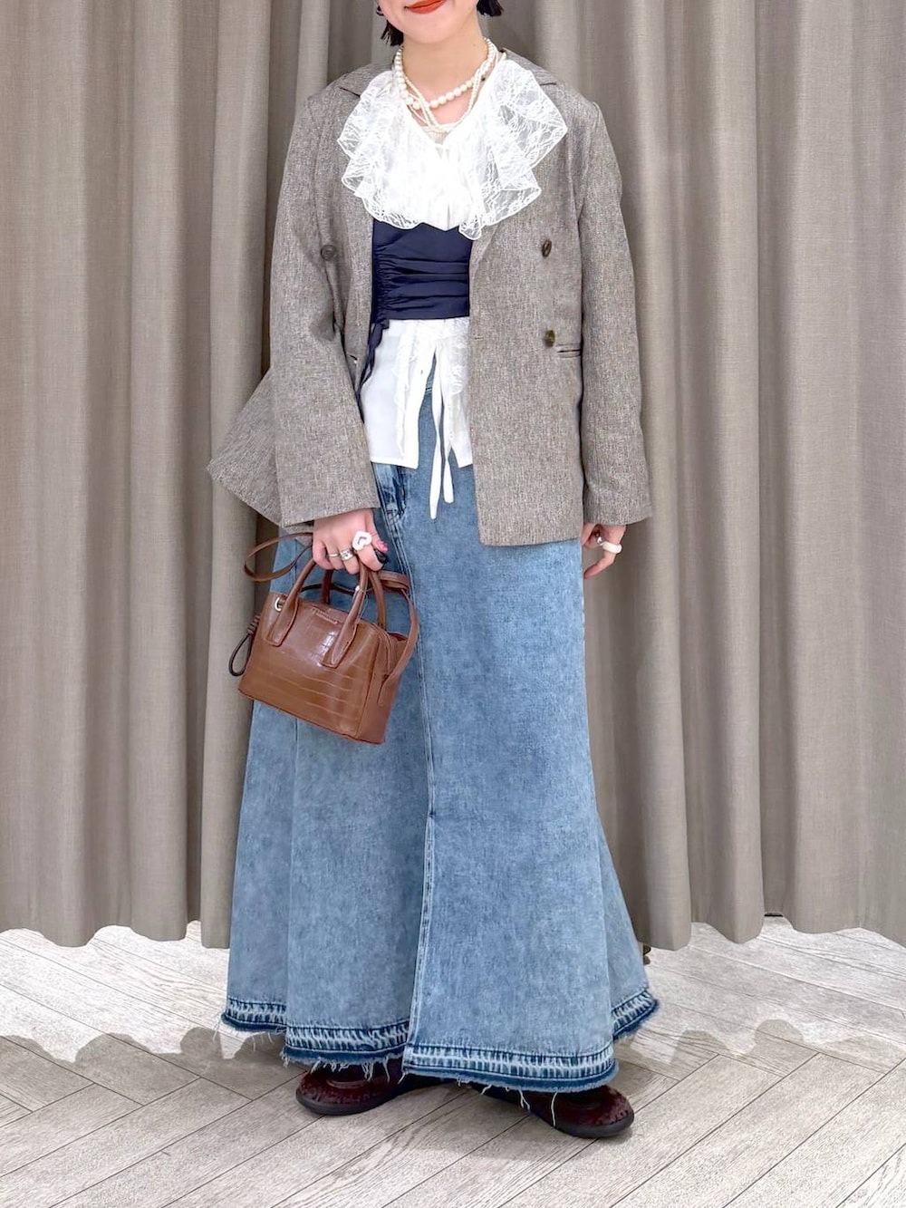 ベージュ系のテーラードジャケット、ブルー系のデニムスカート、ブラウン系のトートバッグを着用したレディースの冬コーディネートの6枚目の写真