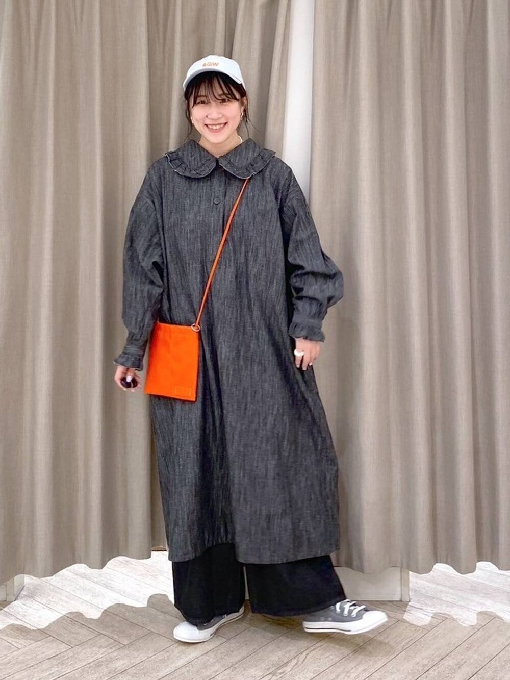 ブラック系のデニムパンツ、グレー系のスニーカー、オレンジ系のショルダーバッグを着用したレディースの秋コーディネートの8枚目の写真