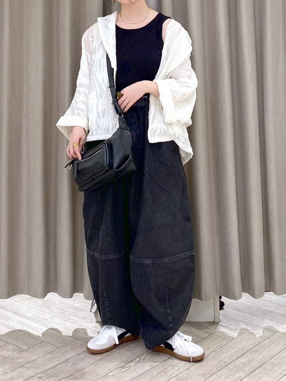 ブラック系のデニムパンツ、ホワイト系のスニーカー、ブラック系のショルダーバッグを着用したレディースの秋コーディネートの7枚目の写真