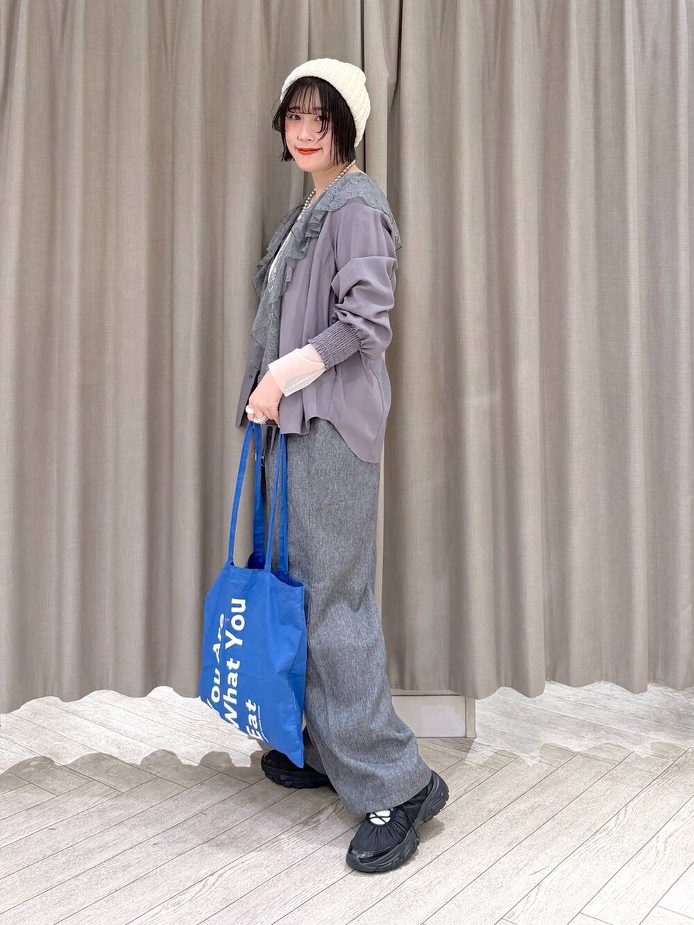 ホワイト系のTシャツ/カットソー、グレー系のスラックス、ブルー系のトートバッグを着用したレディースの冬コーディネートの4枚目の写真