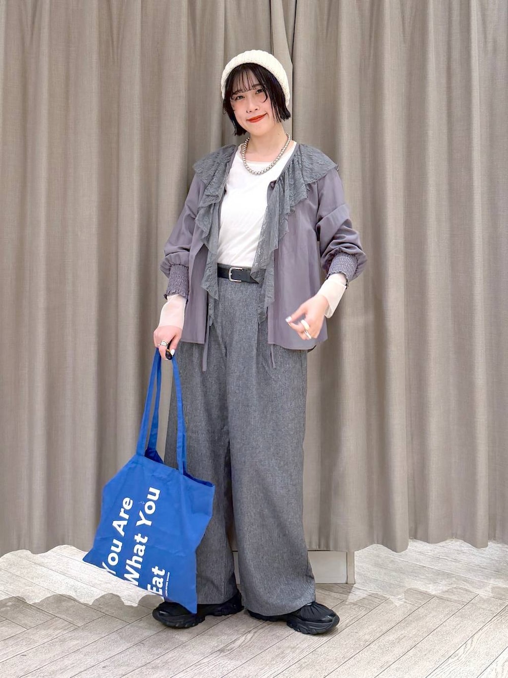 ホワイト系のTシャツ/カットソー、グレー系のスラックス、ブルー系のトートバッグを着用したレディースの冬コーディネートの9枚目の写真