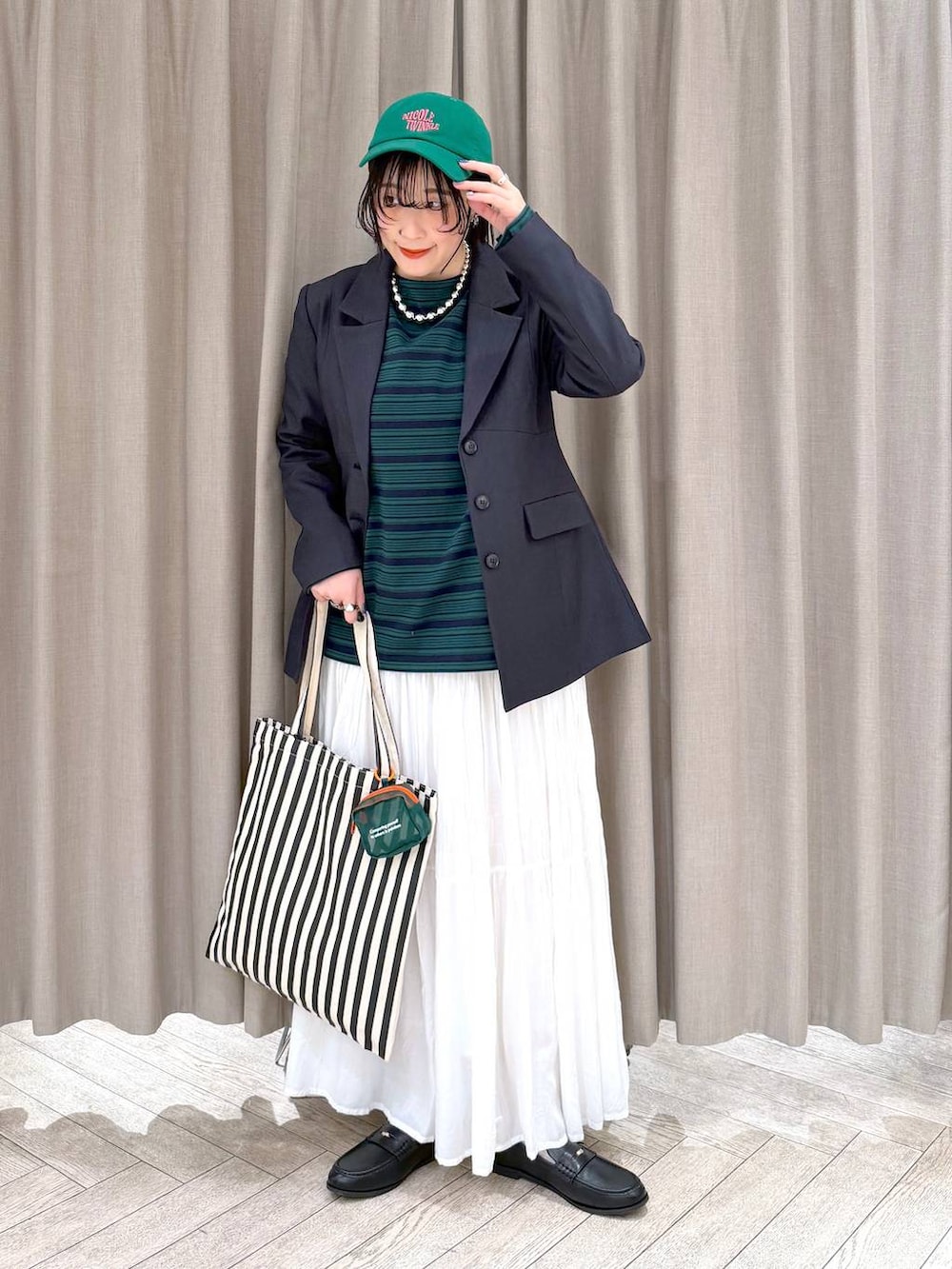 ホワイト系のスカート、ブラック系のローファー、ベージュ系のトートバッグを着用したレディースの冬コーディネートの2枚目の写真