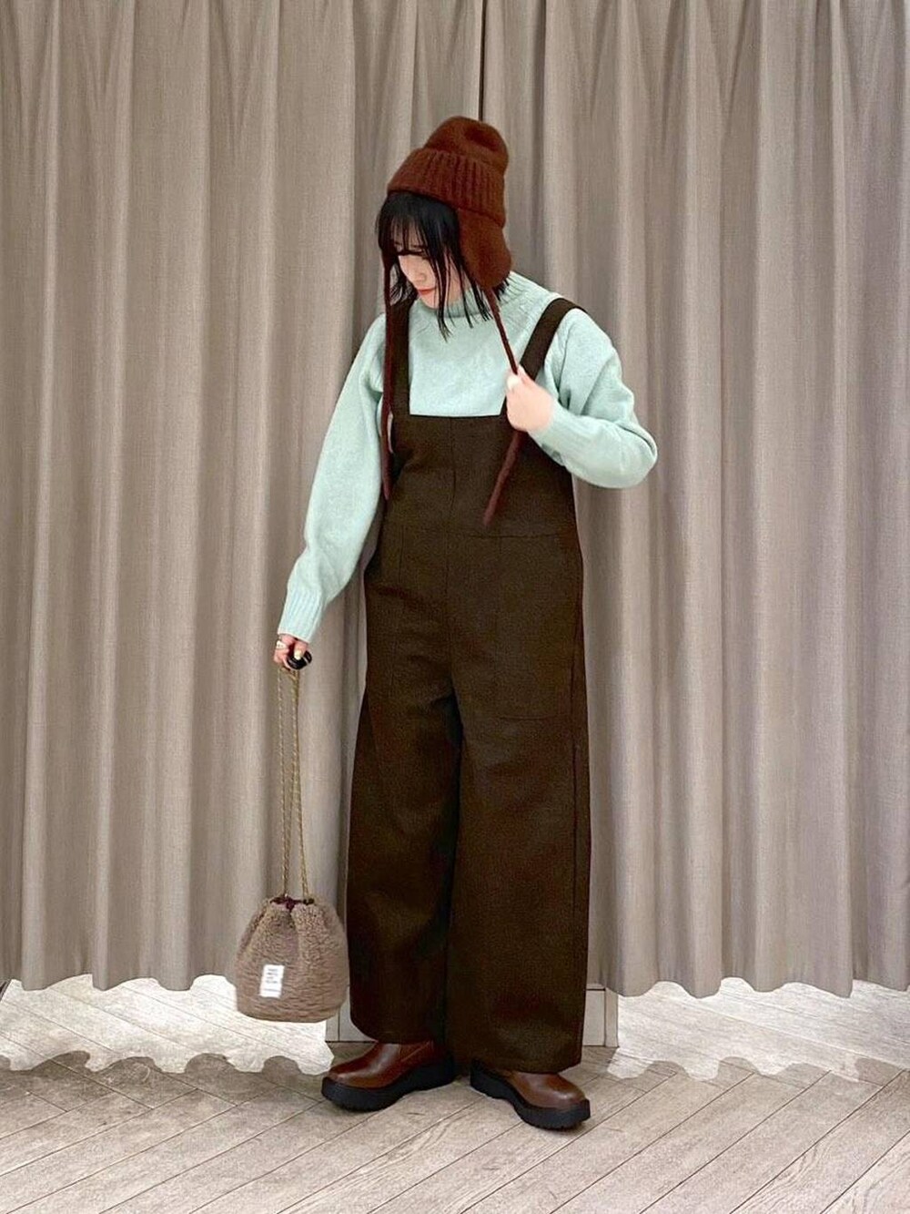 ブラウン系のブーツ、ブラウン系のハンドバッグ、グリーン系のつなぎ/オールインワンを着用したレディースの冬コーディネートの2枚目の写真