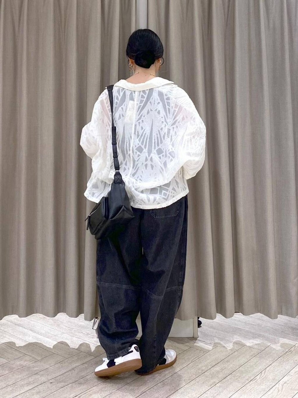 ブラック系のデニムパンツ、ホワイト系のスニーカー、ブラック系のショルダーバッグを着用したレディースの秋コーディネートの4枚目の写真