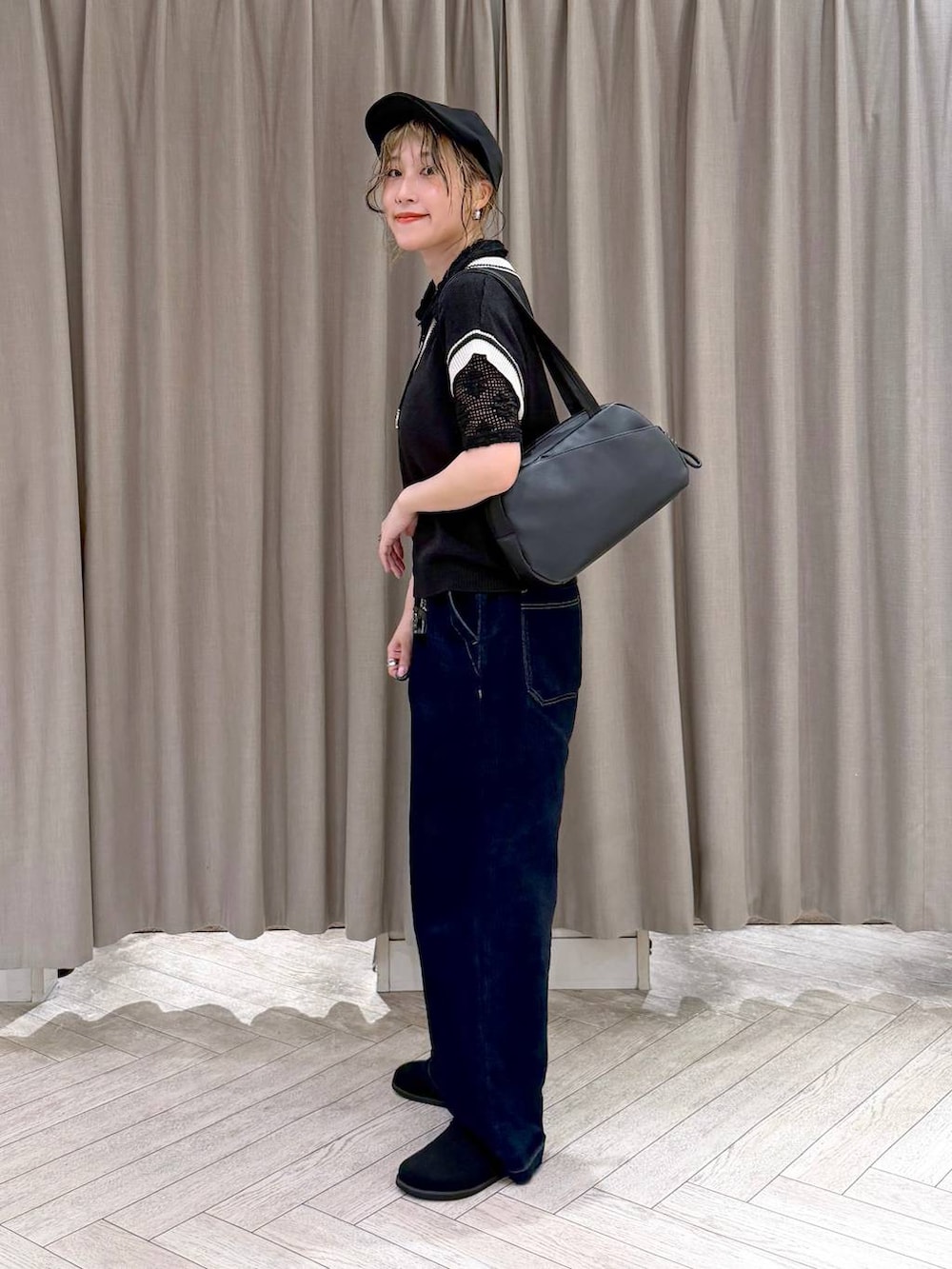 ブラック系のショルダーバッグ、ブラック系のニット/セーター、ブルー系のデニムパンツを着用したレディースの夏コーディネートの3枚目の写真