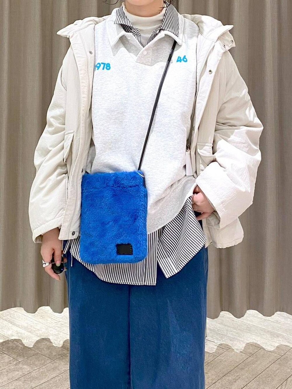 ホワイト系のTシャツ/カットソー、ベージュ系のブルゾン、ブルー系のデニムパンツを着用したレディースの秋コーディネートの7枚目の写真