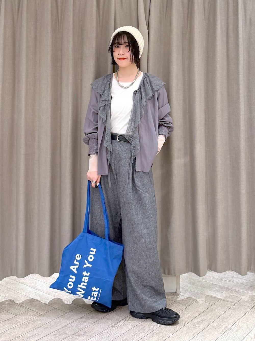 ホワイト系のTシャツ/カットソー、グレー系のスラックス、ブルー系のトートバッグを着用したレディースの冬コーディネートの3枚目の写真