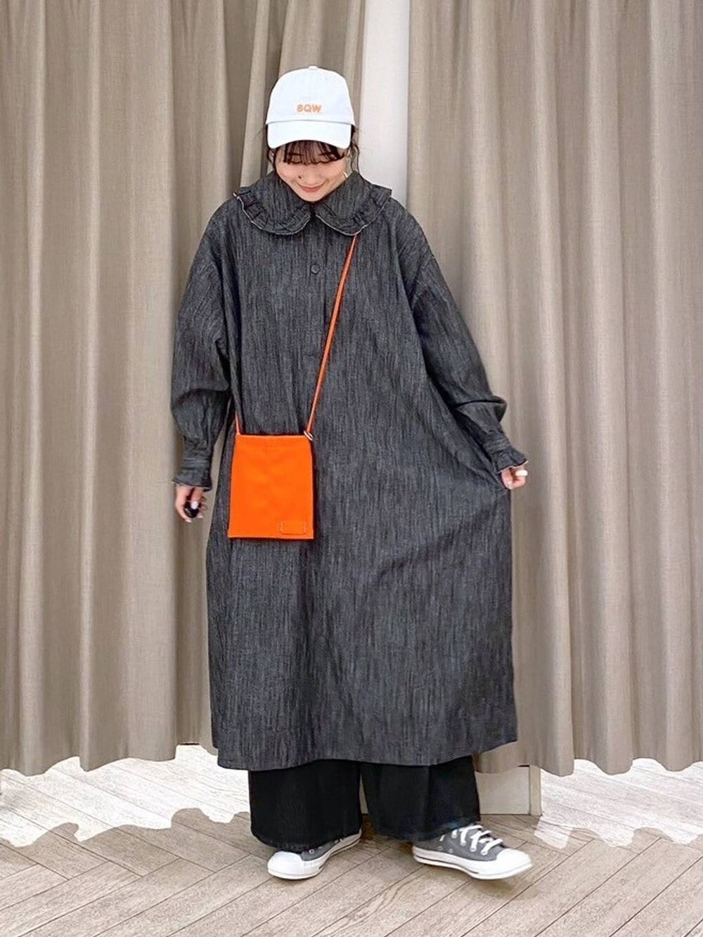 ブラック系のデニムパンツ、グレー系のスニーカー、オレンジ系のショルダーバッグを着用したレディースの秋コーディネートの3枚目の写真