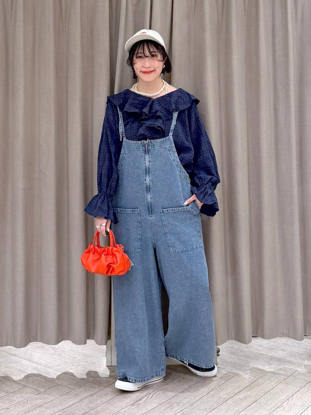 ブルー系のスニーカー、ブルー系のサロペット/オーバーオール、オレンジ系のショルダーバッグを着用したレディースの冬コーディネートの3枚目の写真