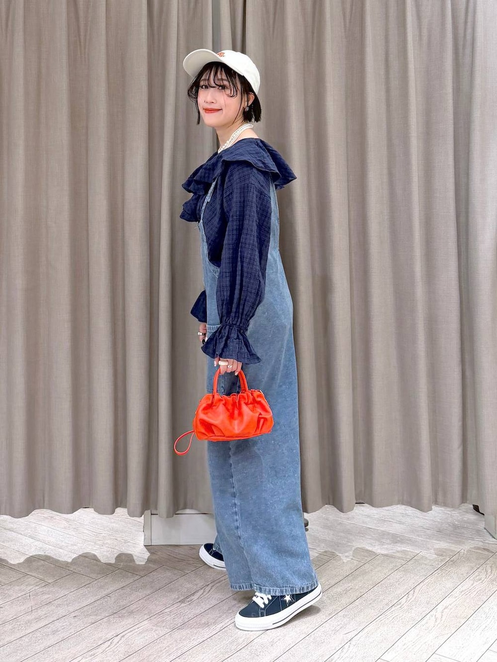 ブルー系のスニーカー、ブルー系のサロペット/オーバーオール、オレンジ系のショルダーバッグを着用したレディースの冬コーディネートの4枚目の写真