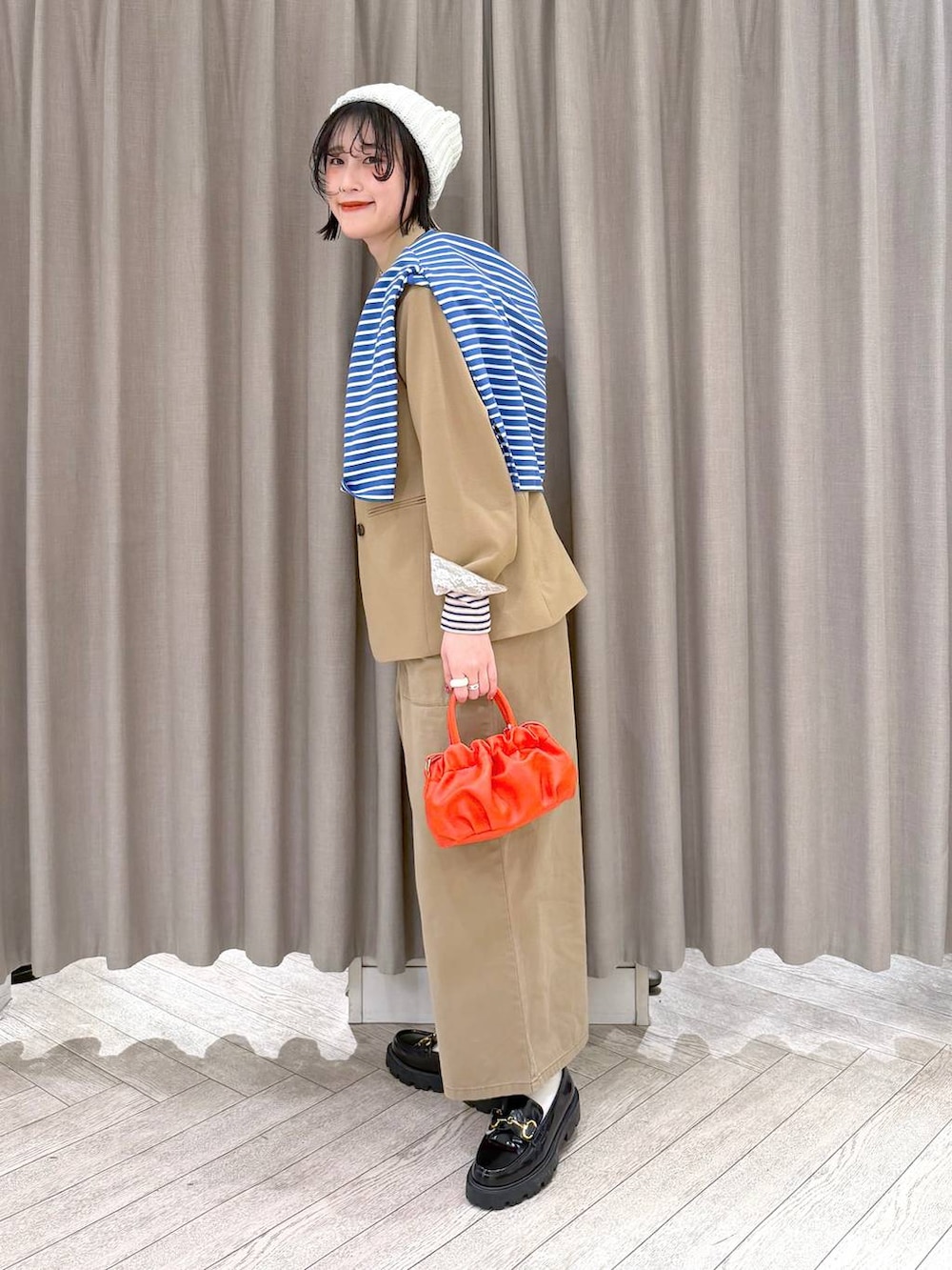ブラック系のローファー、ベージュ系のサロペット/オーバーオール、オレンジ系のショルダーバッグを着用したレディースの冬コーディネートの3枚目の写真