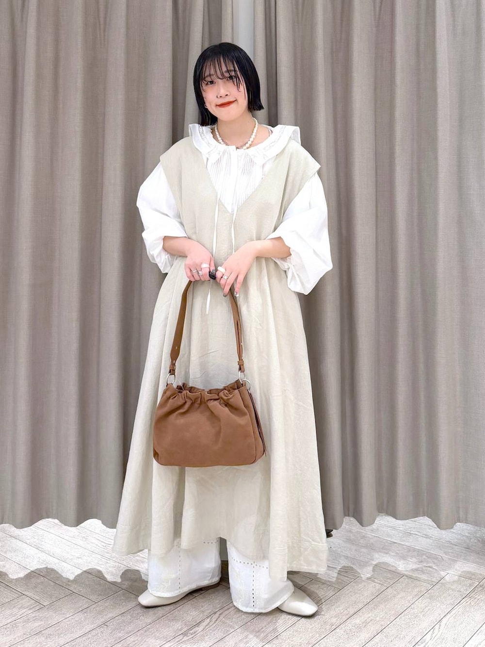 ベージュ系のジャンパースカート、ベージュ系のパンプス、ベージュ系のトートバッグを着用したレディースの冬コーディネートの2枚目の写真