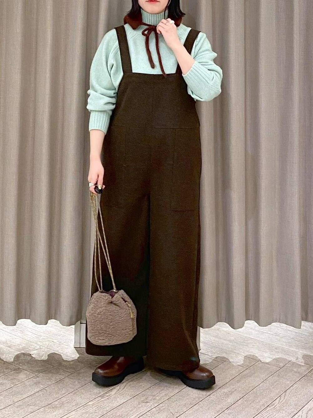 ブラウン系のブーツ、ブラウン系のハンドバッグ、グリーン系のつなぎ/オールインワンを着用したレディースの冬コーディネートの4枚目の写真