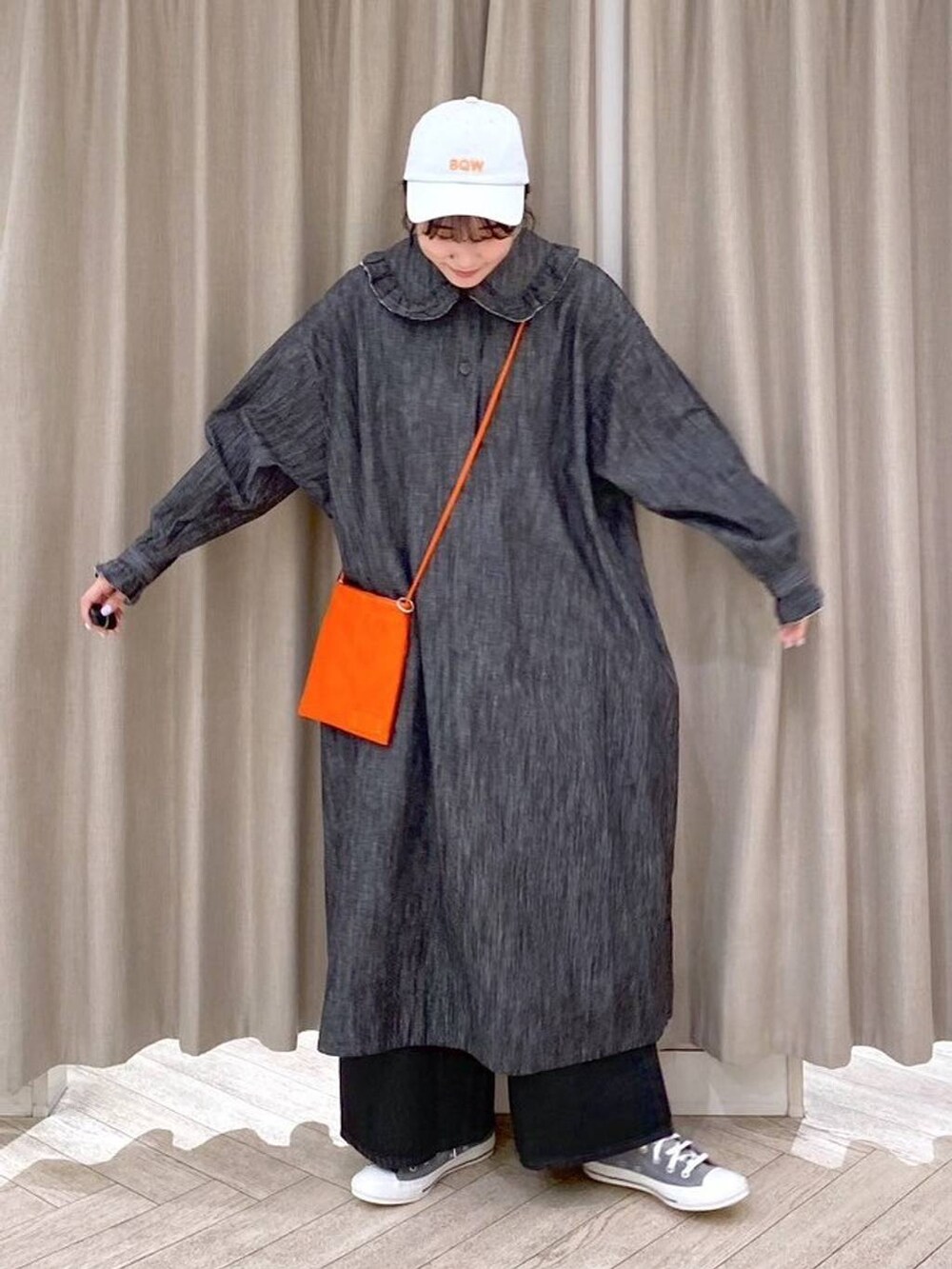 ブラック系のデニムパンツ、グレー系のスニーカー、オレンジ系のショルダーバッグを着用したレディースの秋コーディネートの2枚目の写真