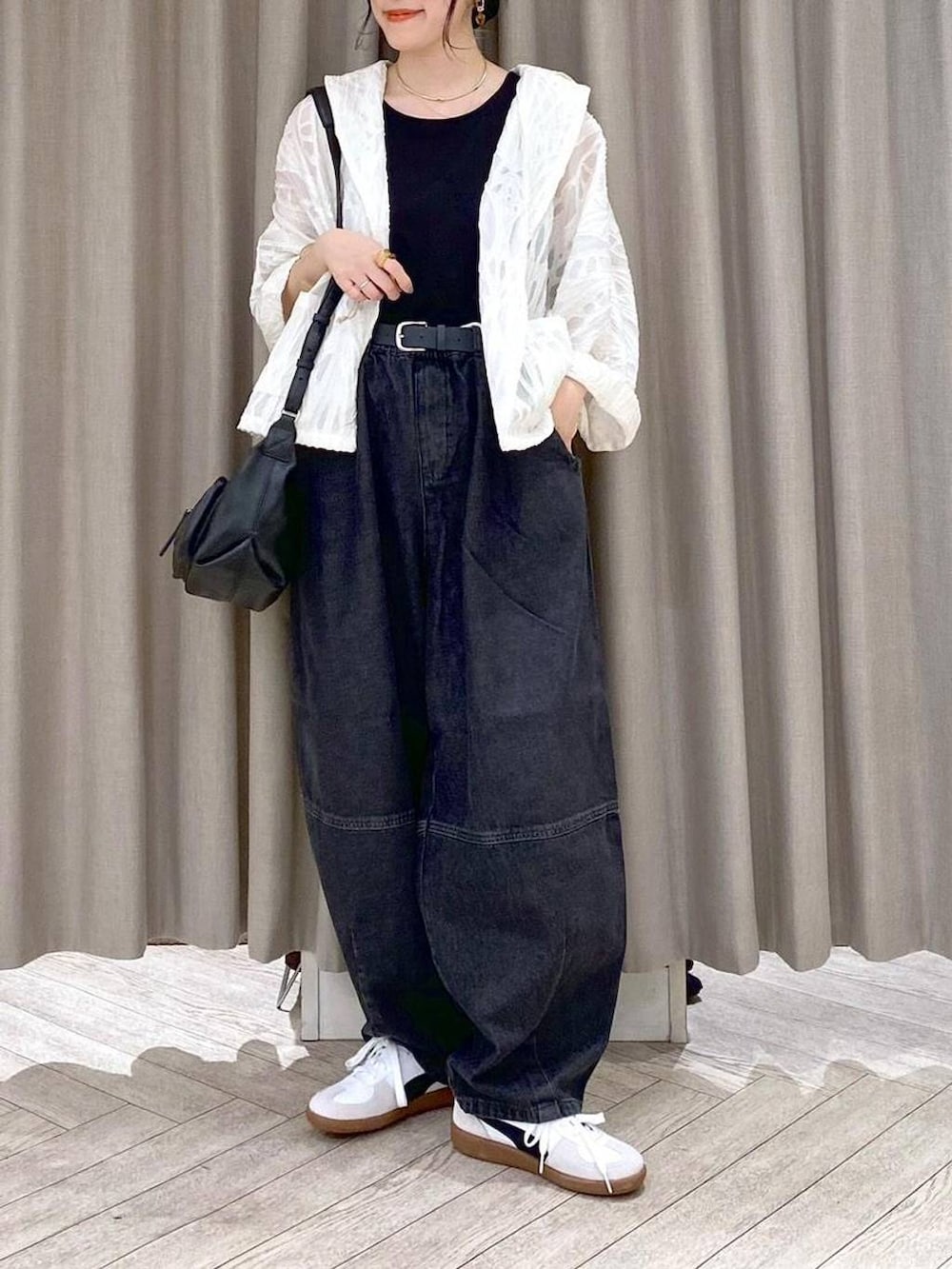 ブラック系のデニムパンツ、ホワイト系のスニーカー、ブラック系のショルダーバッグを着用したレディースの秋コーディネートの6枚目の写真