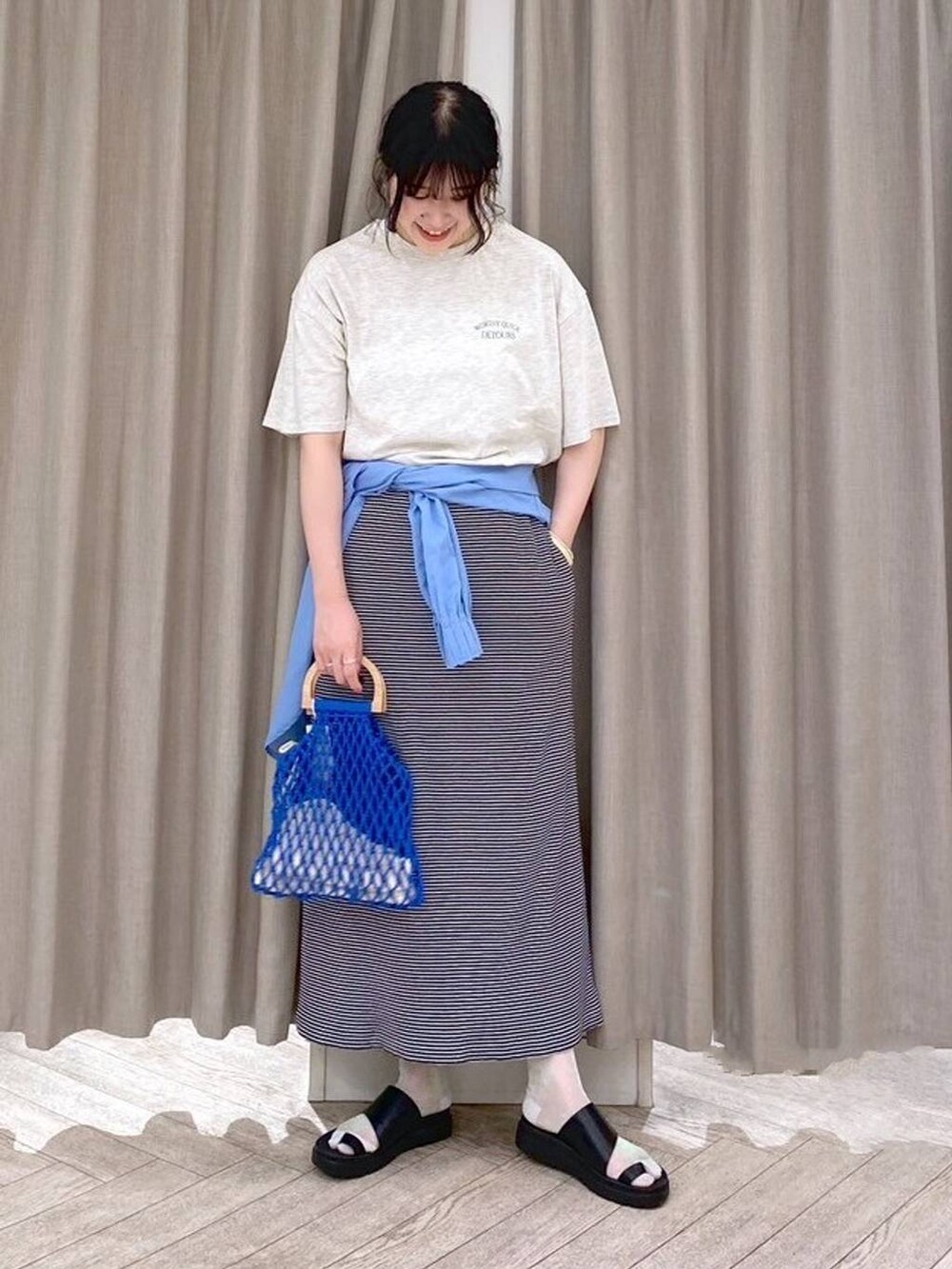 ブラック系のサンダル、ブルー系のハンドバッグ、ブルー系のシャツ/ブラウスを着用したレディースの夏コーディネートの3枚目の写真