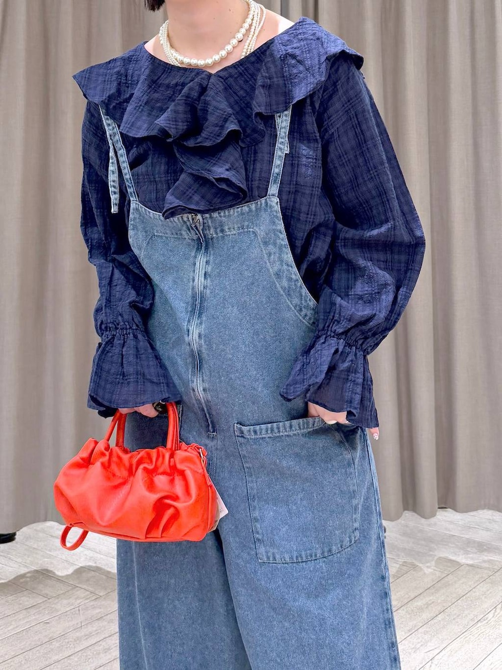 ブルー系のスニーカー、ブルー系のサロペット/オーバーオール、オレンジ系のショルダーバッグを着用したレディースの冬コーディネートの6枚目の写真