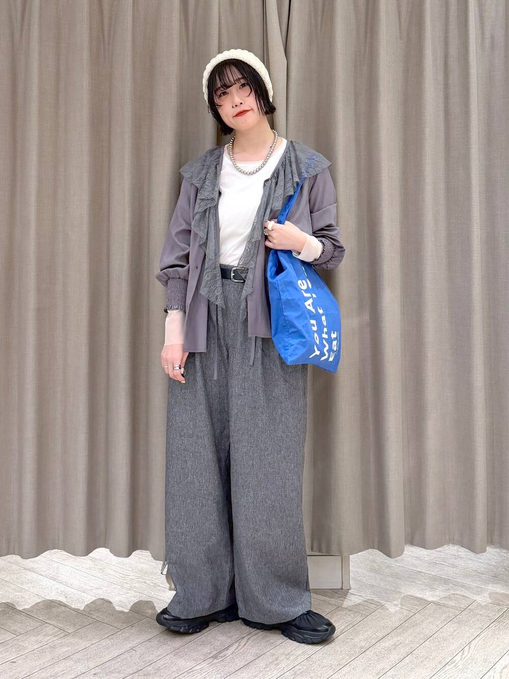 ホワイト系のTシャツ/カットソー、グレー系のスラックス、ブルー系のトートバッグを着用したレディースの冬コーディネートの10枚目の写真