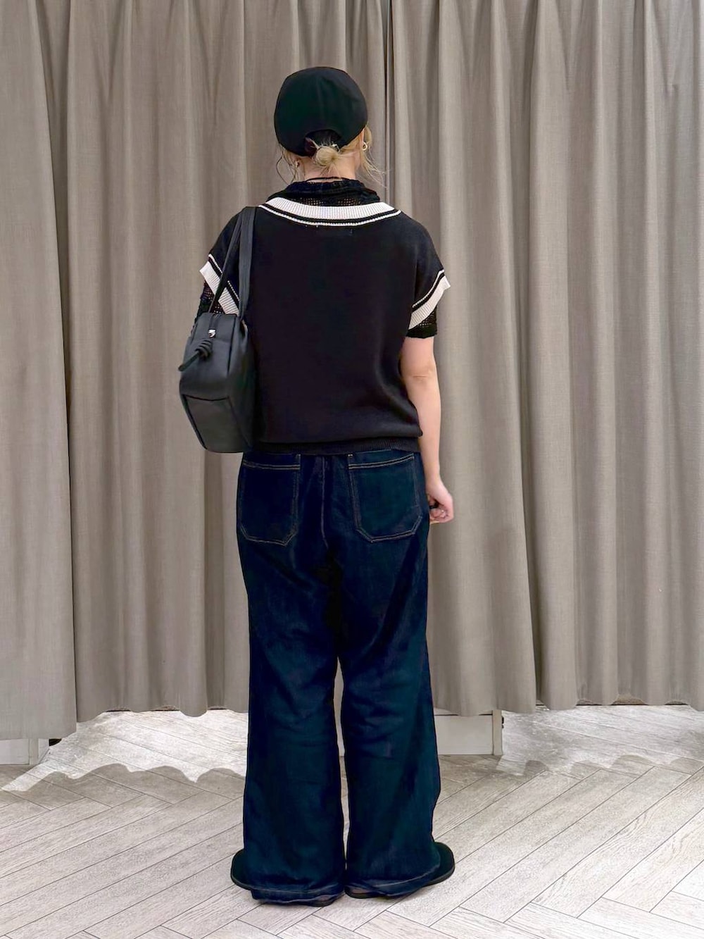 ブラック系のショルダーバッグ、ブラック系のニット/セーター、ブルー系のデニムパンツを着用したレディースの夏コーディネートの4枚目の写真