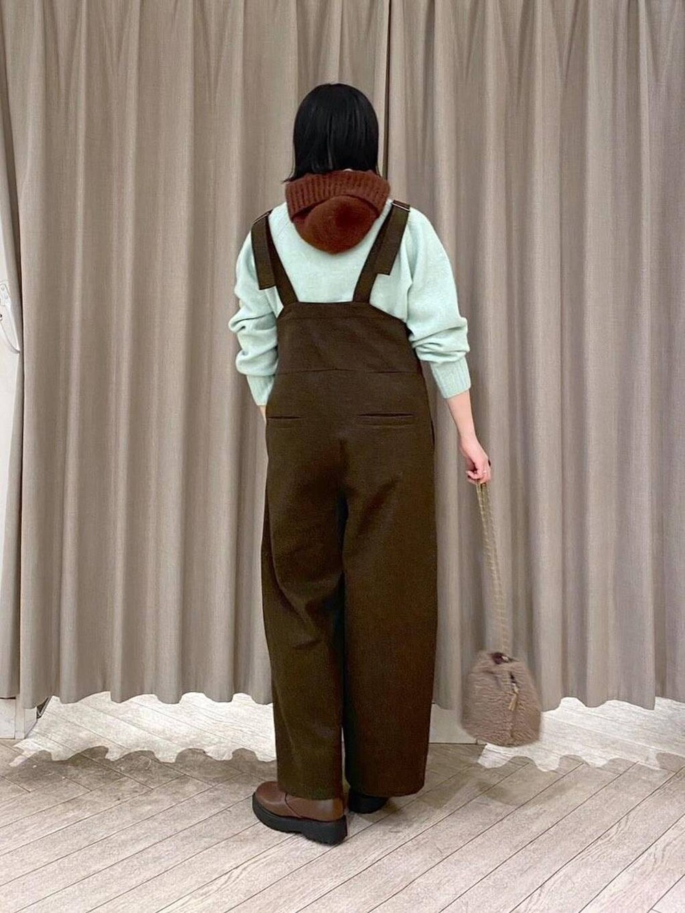 ブラウン系のブーツ、ブラウン系のハンドバッグ、グリーン系のつなぎ/オールインワンを着用したレディースの冬コーディネートの3枚目の写真