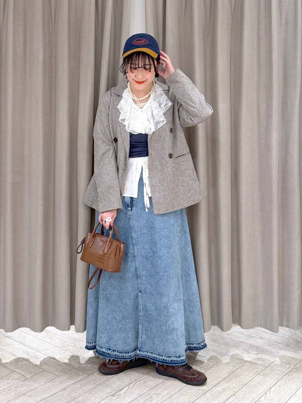 ベージュ系のテーラードジャケット、ブルー系のデニムスカート、ブラウン系のトートバッグを着用したレディースの冬コーディネートの10枚目の写真