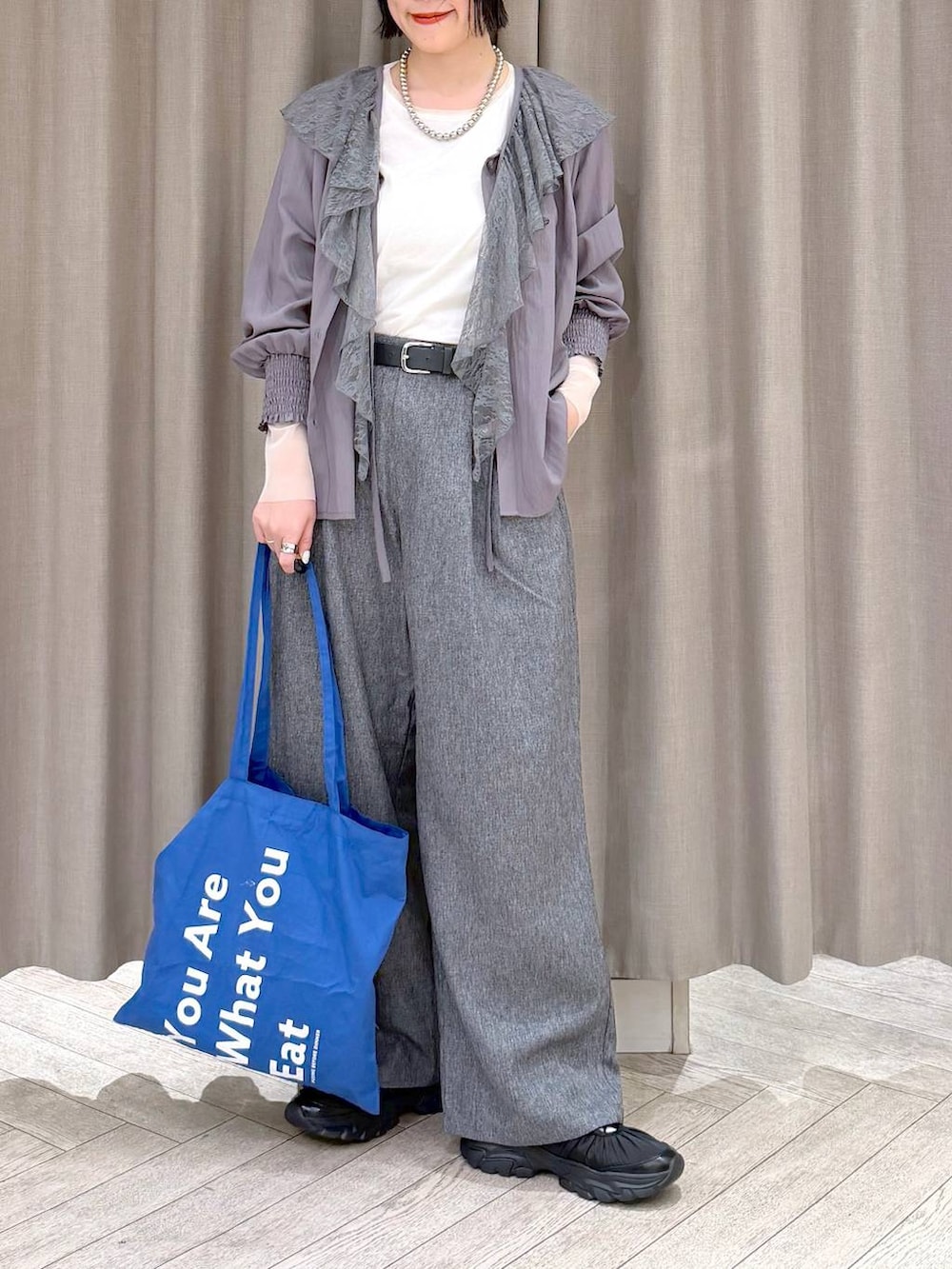 ホワイト系のTシャツ/カットソー、グレー系のスラックス、ブルー系のトートバッグを着用したレディースの冬コーディネートの8枚目の写真