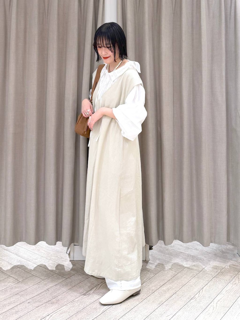 ベージュ系のジャンパースカート、ベージュ系のパンプス、ベージュ系のトートバッグを着用したレディースの冬コーディネートの4枚目の写真