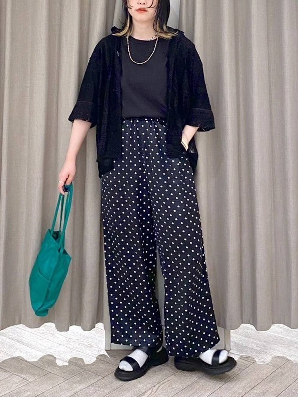 ブラック系のTシャツ/カットソー、ブラック系のサンダル、グリーン系のショルダーバッグを着用したレディースの春コーディネートの6枚目の写真