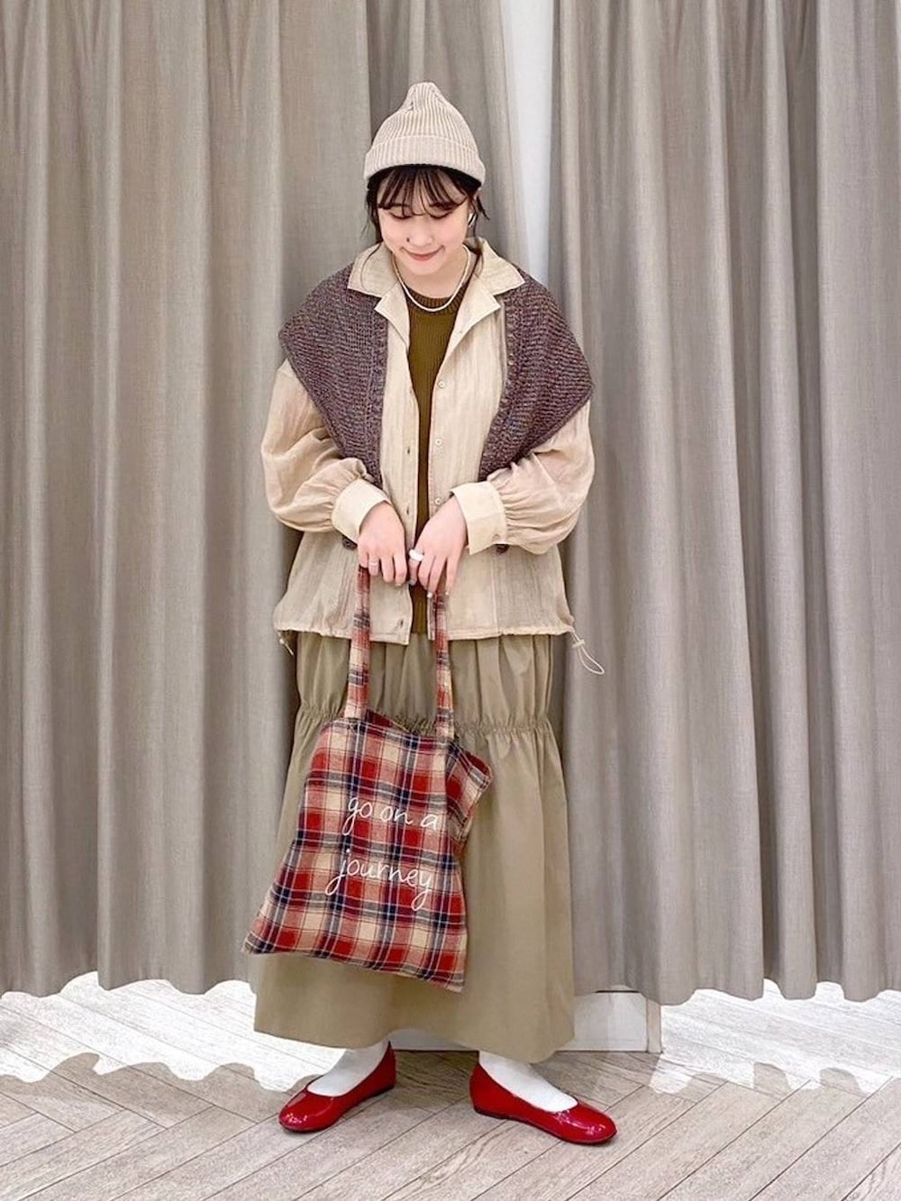 レッド系のパンプス、ベージュ系のナイロンジャケット、ベージュ系のワンピースを着用したレディースの秋コーディネートの2枚目の写真