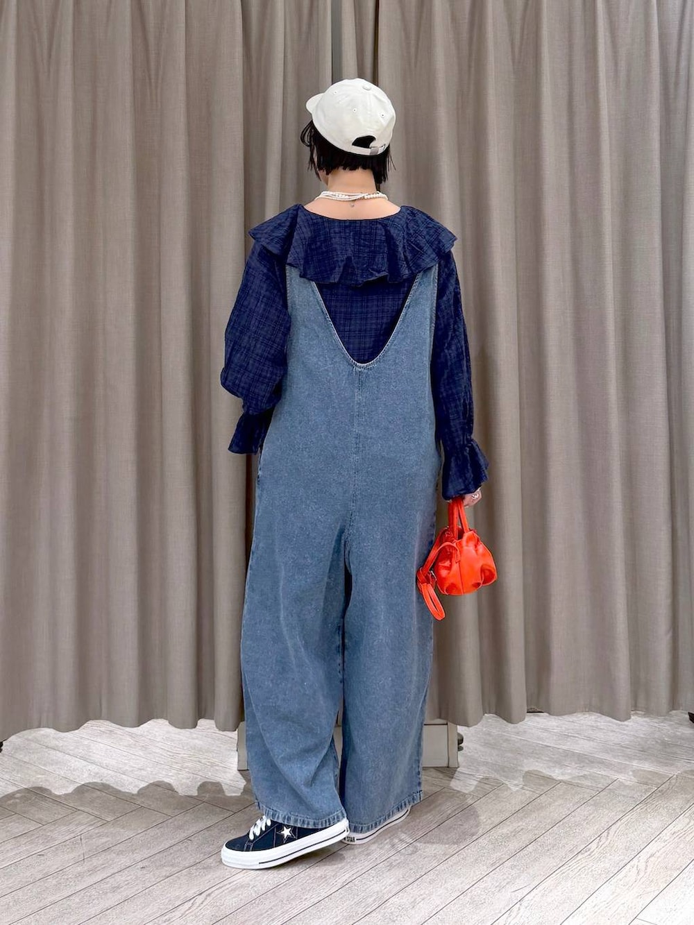 ブルー系のスニーカー、ブルー系のサロペット/オーバーオール、オレンジ系のショルダーバッグを着用したレディースの冬コーディネートの5枚目の写真