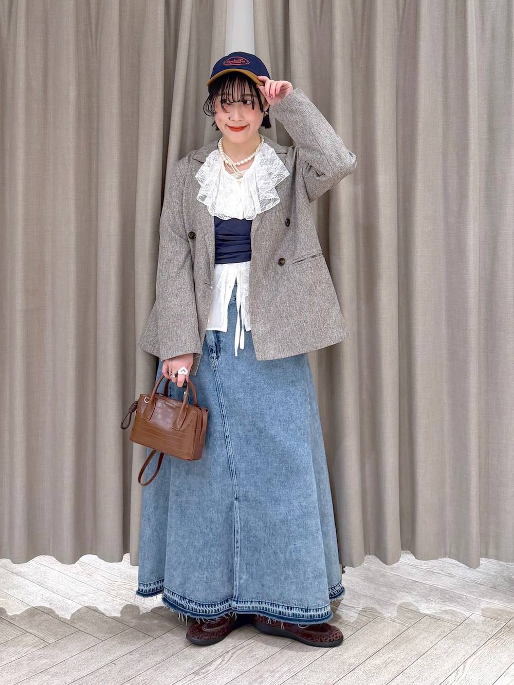ベージュ系のテーラードジャケット、ブルー系のデニムスカート、ブラウン系のトートバッグを着用したレディースの冬コーディネートの2枚目の写真