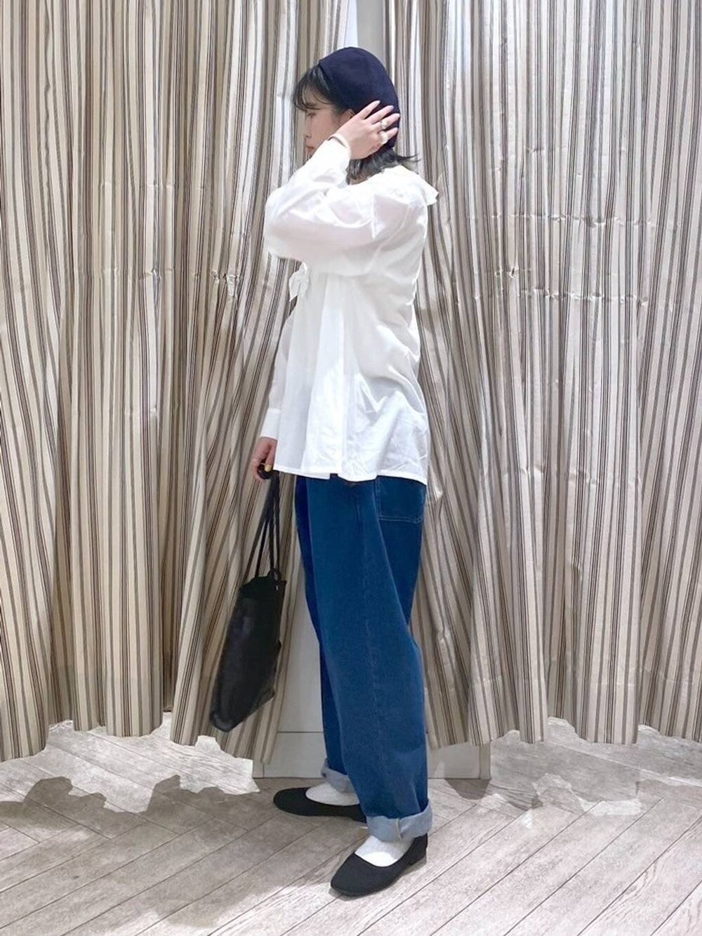 ホワイト系のシャツ/ブラウス、ベージュ系のタンクトップ、ブルー系のデニムパンツを着用したレディースの春コーディネートの7枚目の写真