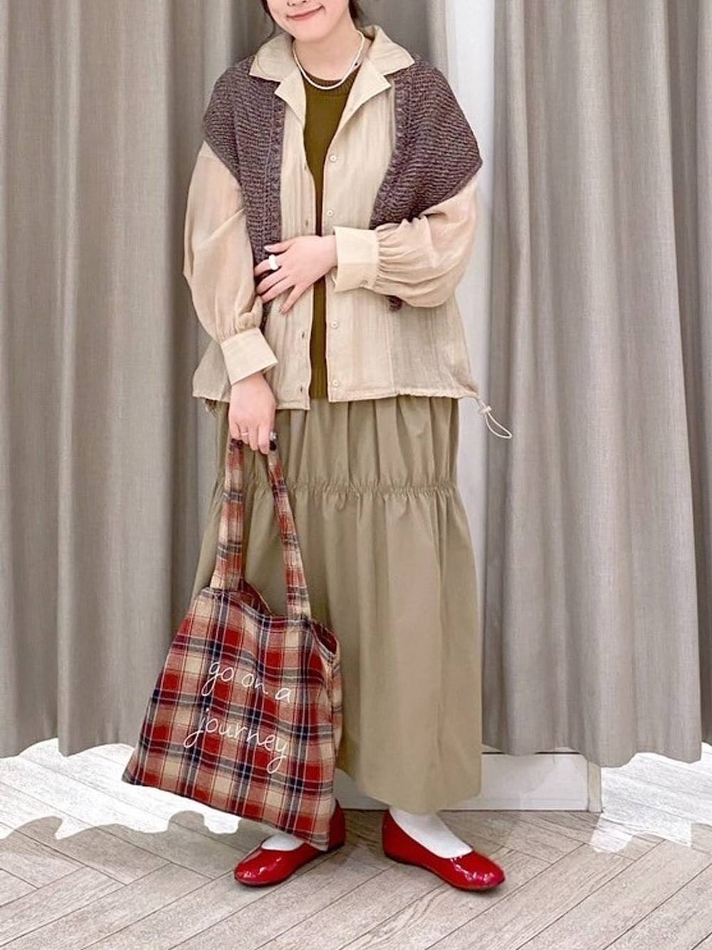 レッド系のパンプス、ベージュ系のナイロンジャケット、ベージュ系のワンピースを着用したレディースの秋コーディネートの6枚目の写真