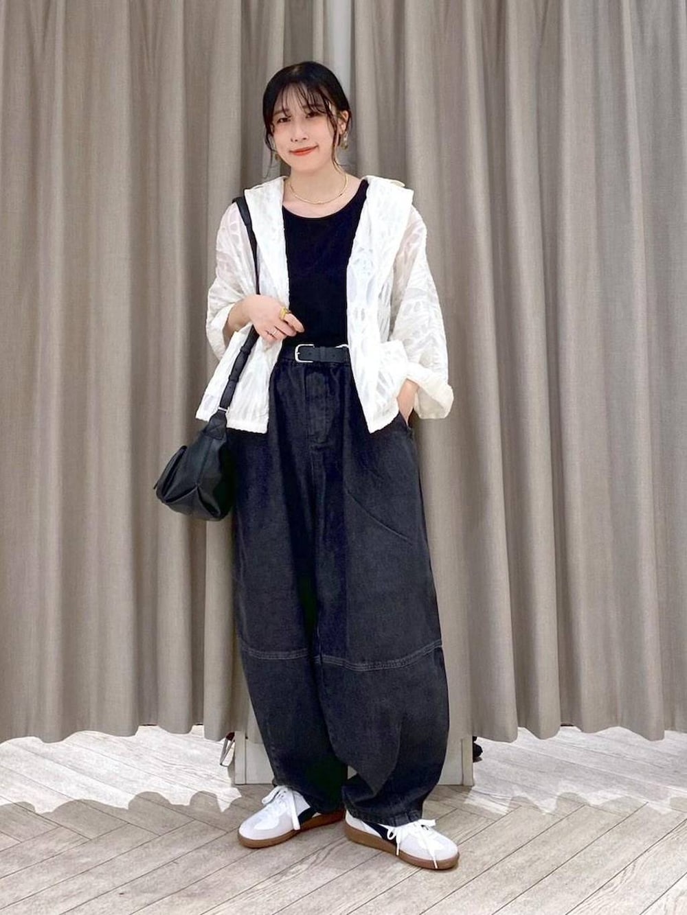 ブラック系のデニムパンツ、ホワイト系のスニーカー、ブラック系のショルダーバッグを着用したレディースの秋コーディネートの9枚目の写真