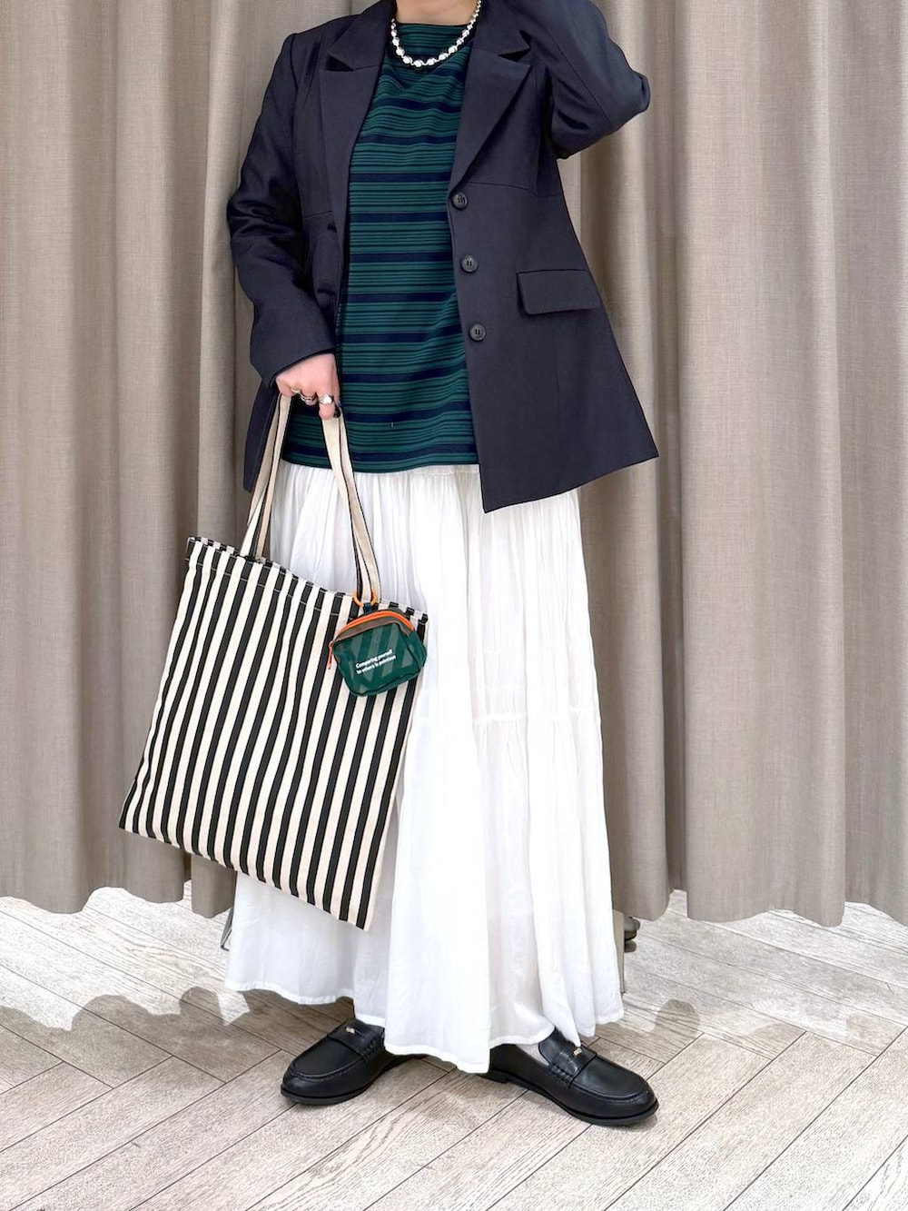 ホワイト系のスカート、ブラック系のローファー、ベージュ系のトートバッグを着用したレディースの冬コーディネートの8枚目の写真