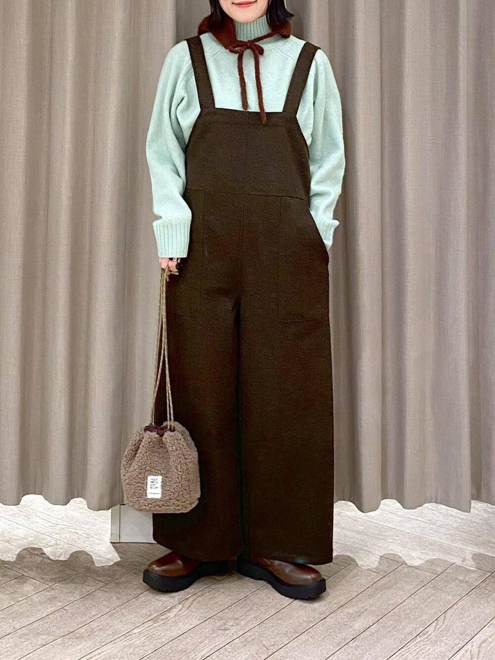 ブラウン系のブーツ、ブラウン系のハンドバッグ、グリーン系のつなぎ/オールインワンを着用したレディースの冬コーディネートの5枚目の写真