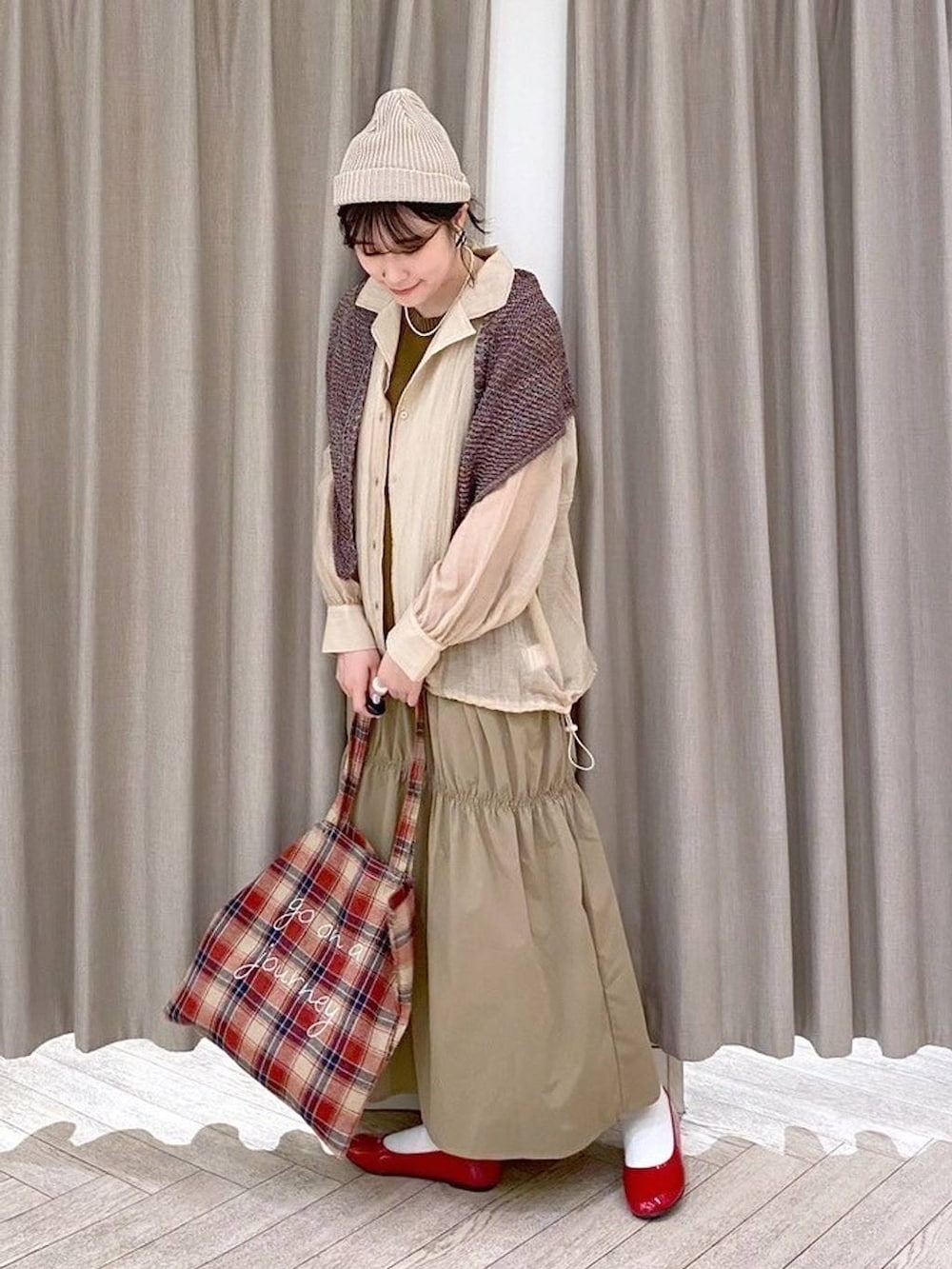 レッド系のパンプス、ベージュ系のナイロンジャケット、ベージュ系のワンピースを着用したレディースの秋コーディネートの3枚目の写真