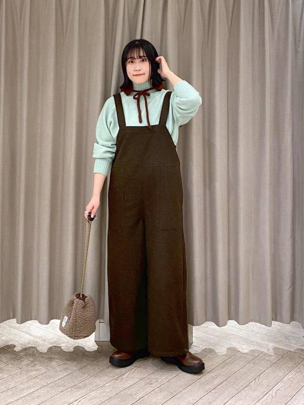 ブラウン系のブーツ、ブラウン系のハンドバッグ、グリーン系のつなぎ/オールインワンを着用したレディースの冬コーディネートの7枚目の写真