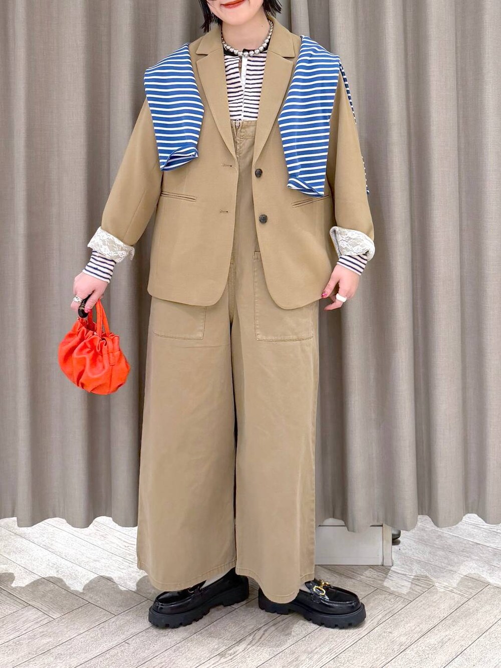 ブラック系のローファー、ベージュ系のサロペット/オーバーオール、オレンジ系のショルダーバッグを着用したレディースの冬コーディネートの6枚目の写真