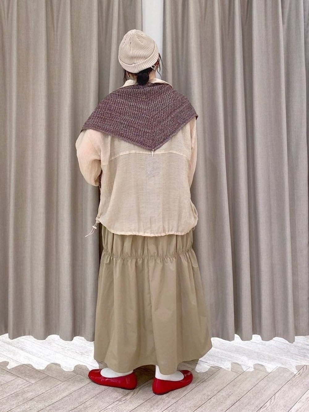 レッド系のパンプス、ベージュ系のナイロンジャケット、ベージュ系のワンピースを着用したレディースの秋コーディネートの4枚目の写真