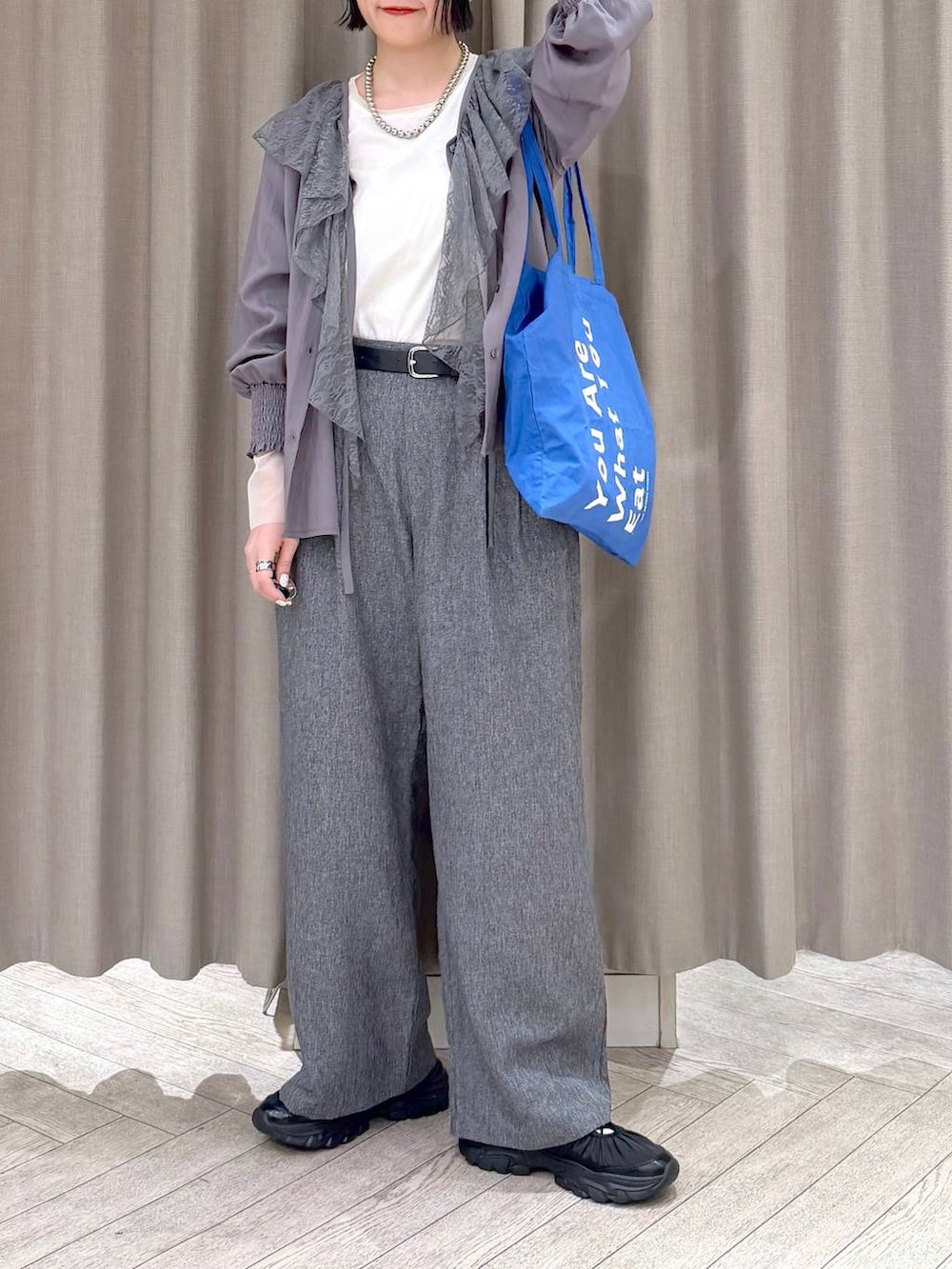 ホワイト系のTシャツ/カットソー、グレー系のスラックス、ブルー系のトートバッグを着用したレディースの冬コーディネートの7枚目の写真